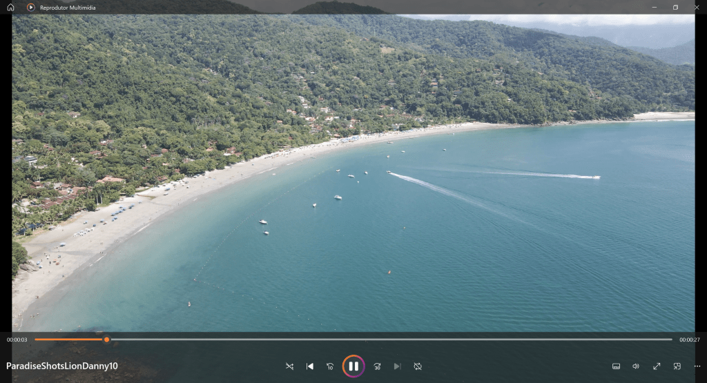 Aerial photograph of a white-sand beach, colorful teal sea, surrounded by  green mountains. Part of the ''Paradise'' Collection